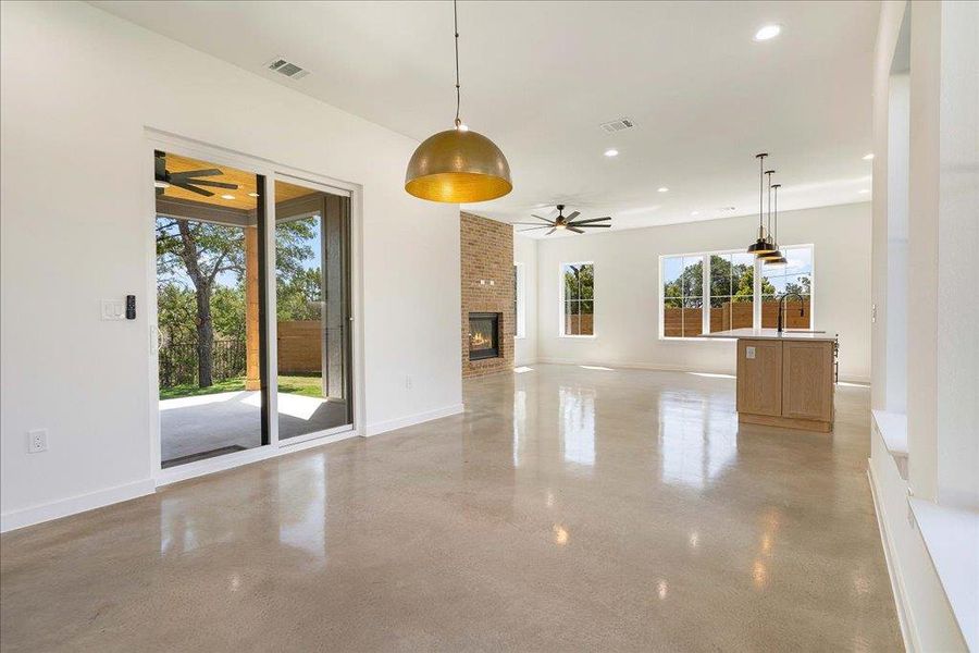 Unfurnished living room featuring a ceiling fan, a fireplace, concrete floors, and recessed lighting