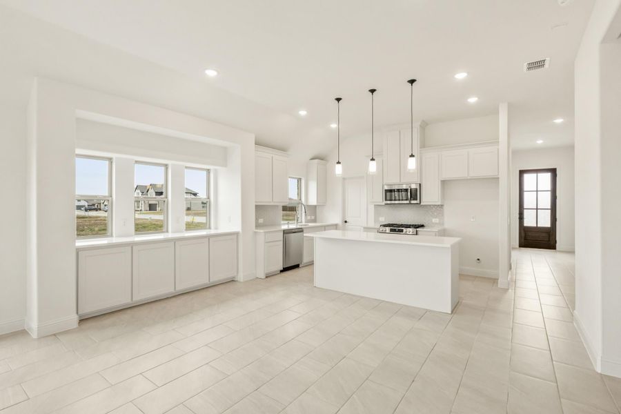Open kitchen with white cabinets, center island, pendant lights, and stainless steel appliances