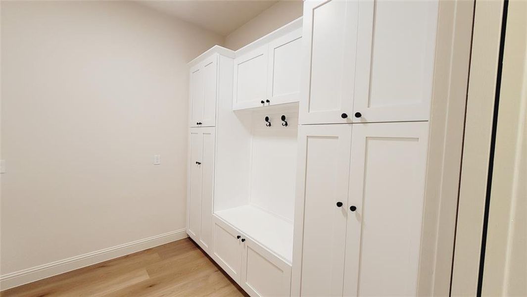 Built-in white shaker cabinetry with black hardware, integrated bench seating, and wood-finish flooring