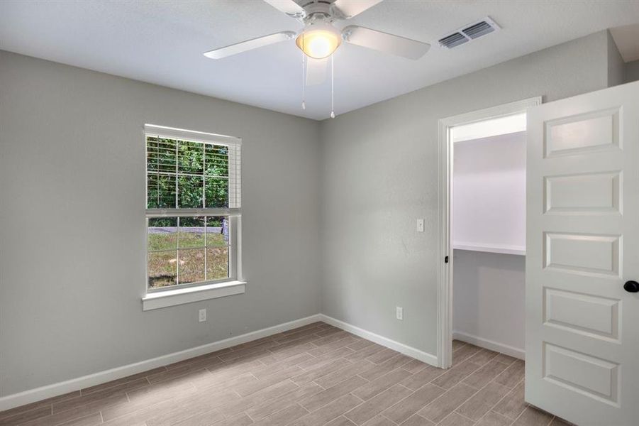 Unfurnished bedroom with wood tiled floors and a ceiling fan Unfurnished bedroom with wood tiled floors and a ceiling fan