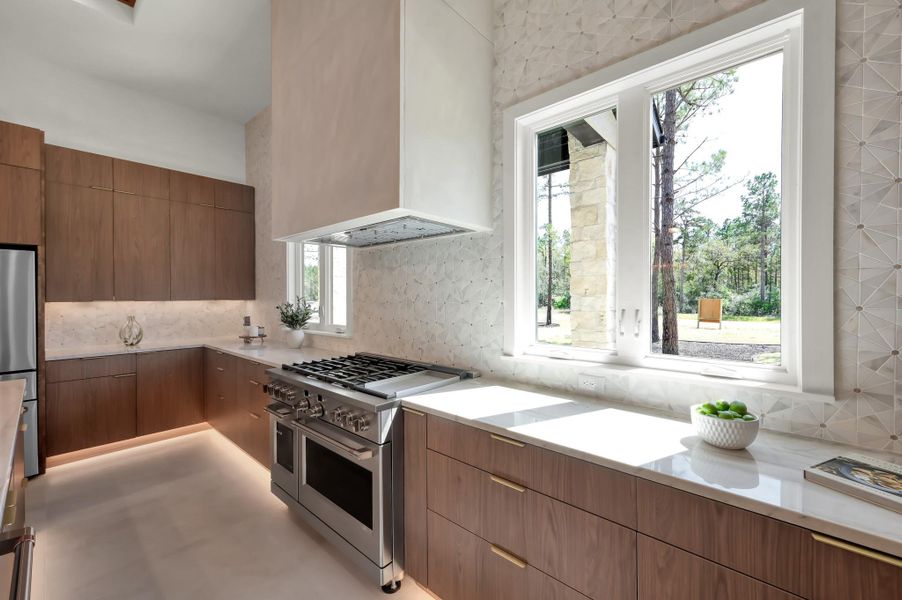 A chef’s kitchen designed to impress—featuring premium Café™ appliances, a 48” commercial-style dual-fuel range, custom vent hood, and dual oversized islands that anchor the space.