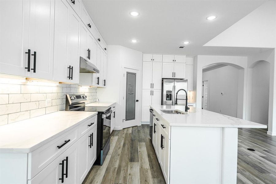 A well-lit, open-concept kitchen features bright white cabinetry and modern appliances for a pristine look. A well-lit, open-concept kitchen features bright white cabinetry and modern appliances for a pristine look.