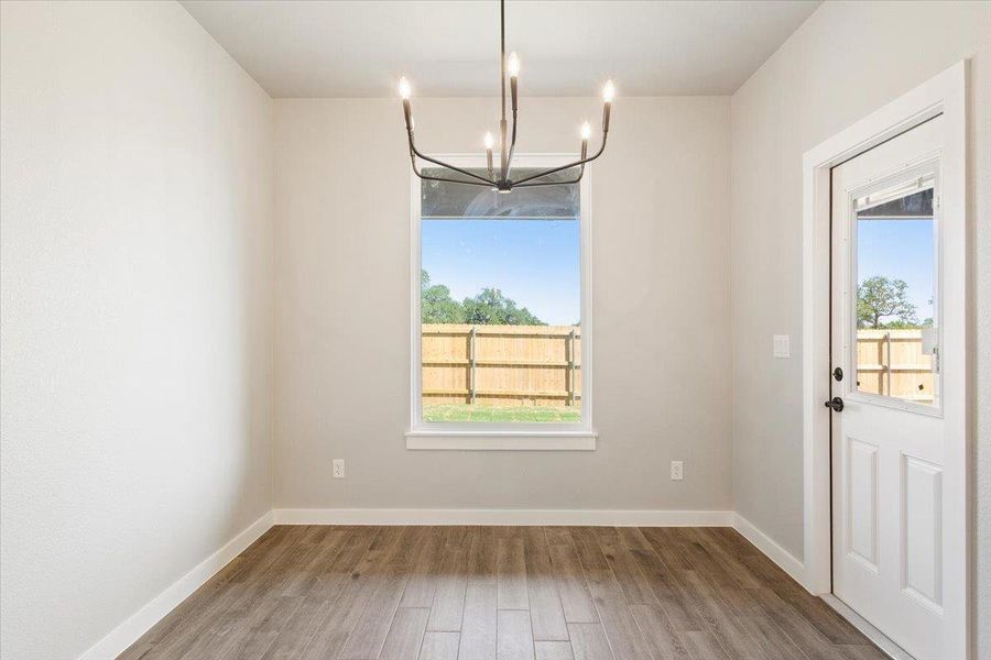 Unfurnished dining area with wood finished floors and a chandelier