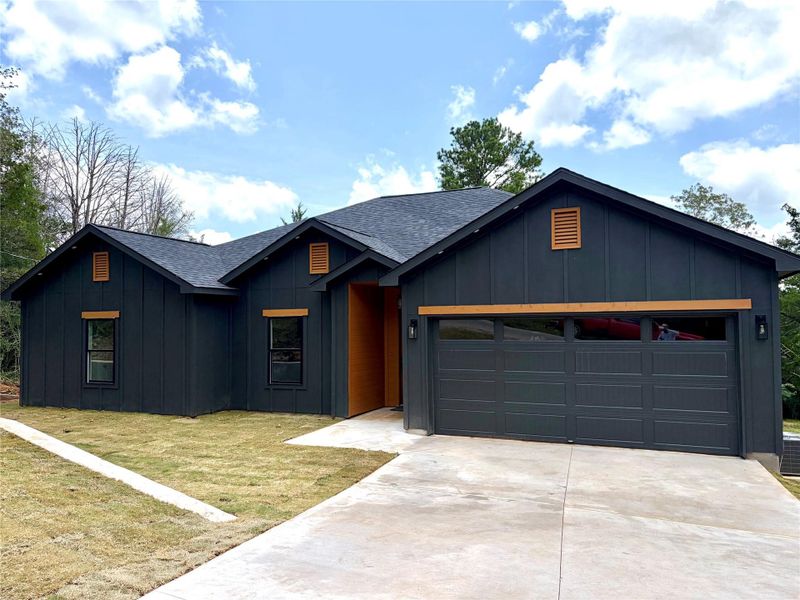 A modern facade with board and batten siding, featuring a two-car garage and a concrete driveway. A modern facade with board and batten siding, featuring a two-car garage and a concrete driveway.