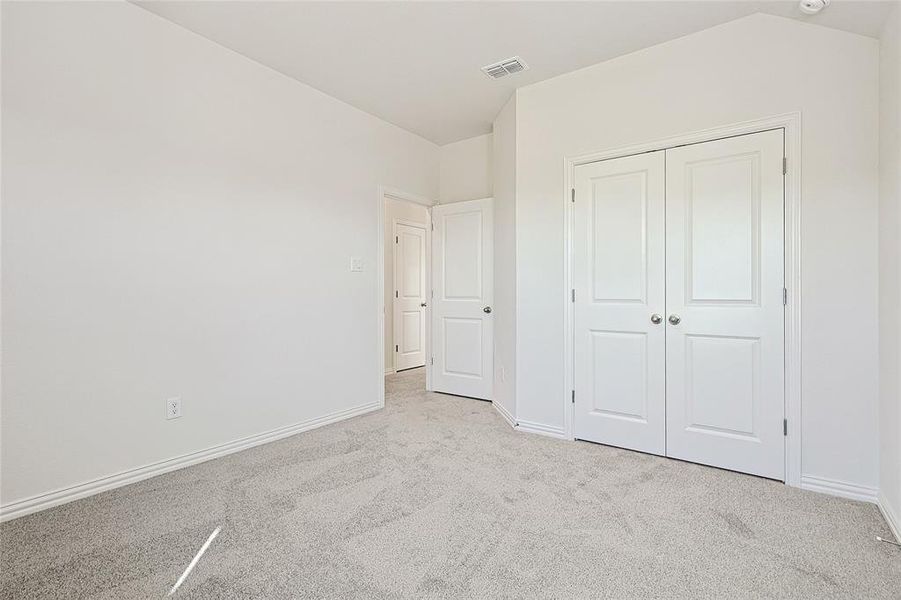 Unfurnished bedroom with light carpet and a closet
