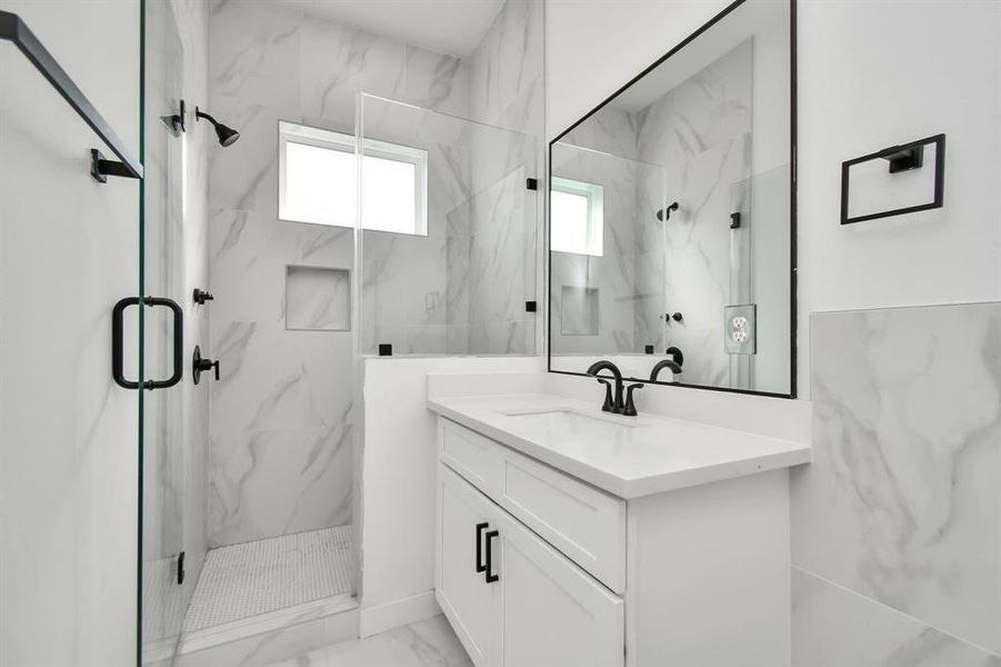 Refresh and revitalize in the modern comfort of the primary bath’s spacious glass frame walk-in shower