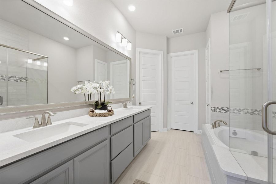 Primary Bath features dual sinks, a soaking tub, and a separate glass-enclosed walk-in shower.