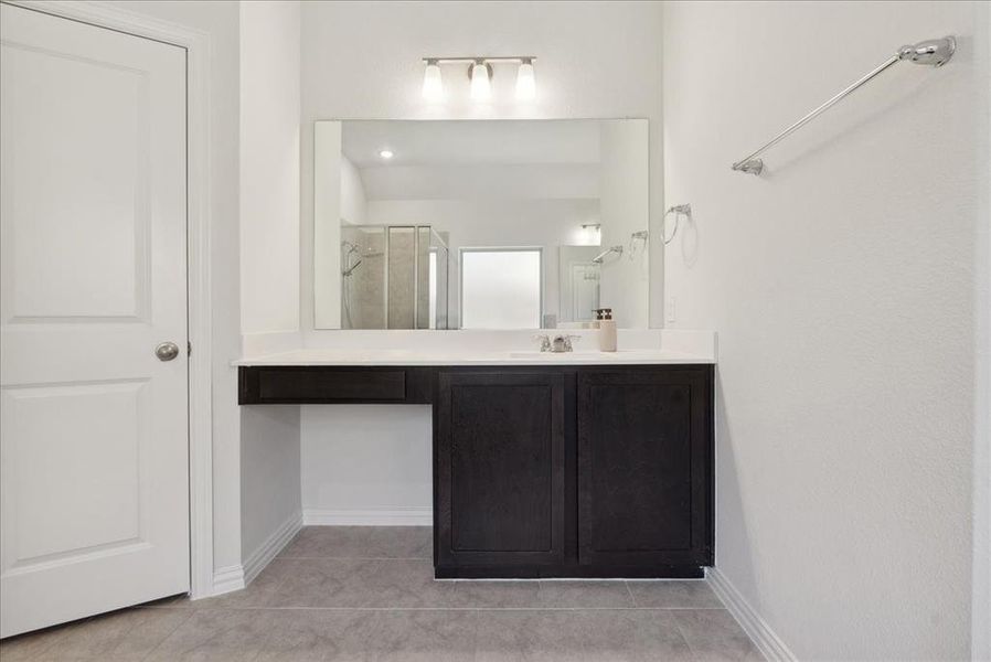 Bathroom with tile patterned flooring, vanity, and a shower with door