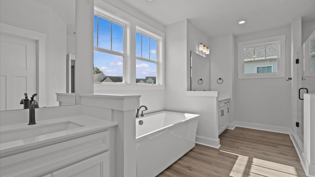 Superior en-suite primary bathroom with stylish vanities, tiled walk-in shower, and soaking tub
