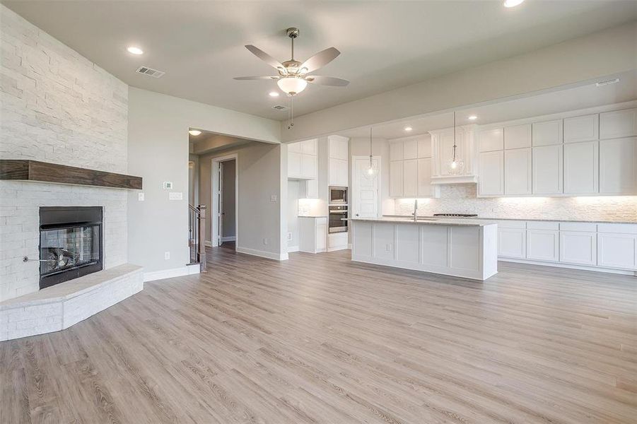 Kitchen with light hardwood / wood-style floors, white cabinetry, a kitchen island with sink, and appliances with stainless steel finishes