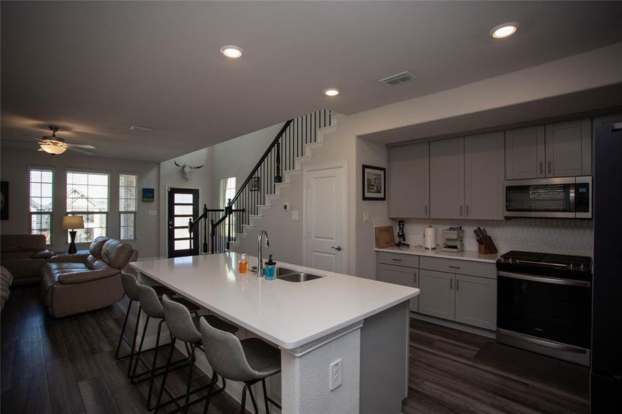Kitchen featuring visible vents, open floor plan, a kitchen breakfast bar, stainless steel appliances, and a sink