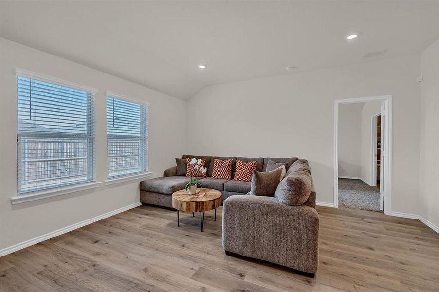 Living area with baseboards, light wood-style floors, vaulted ceiling, and recessed lighting