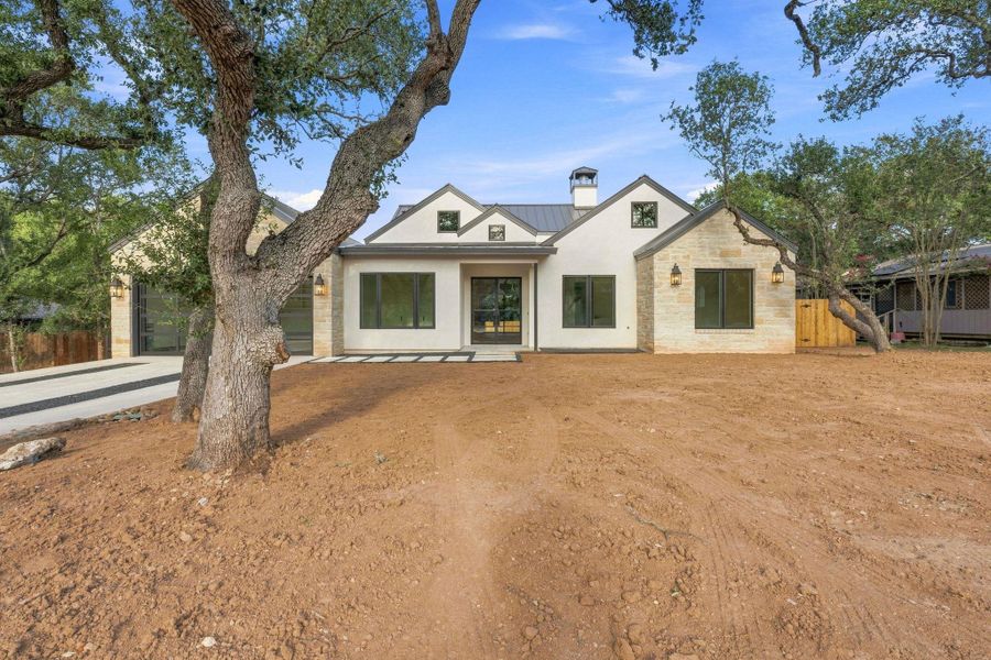 Mature trees frame the striking stone and stucco facade of this modern custom home.