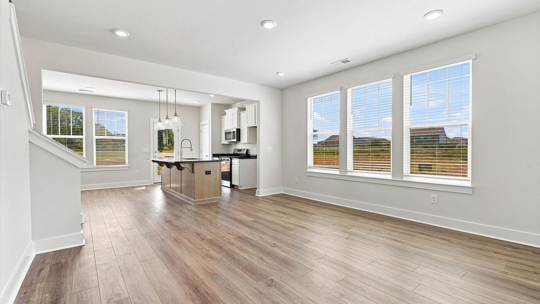 Elegant family room featuring hardwood flooring, large windows, and thoughtful architectural detail Elegant family room featuring hardwood flooring, large windows, and thoughtful architectural detail