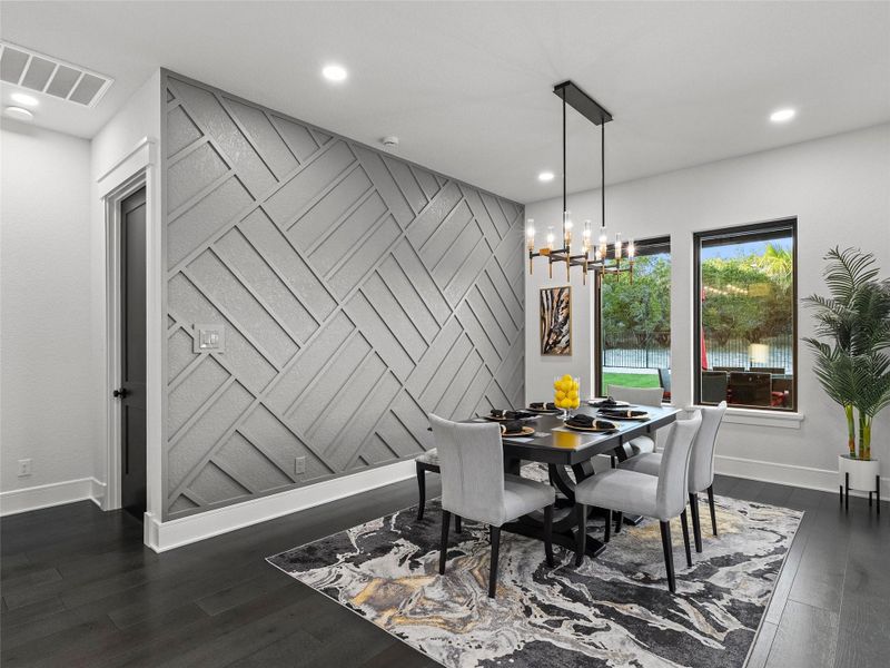 Dining room with an accent wall, dark wood-style floors, and suspended lighting