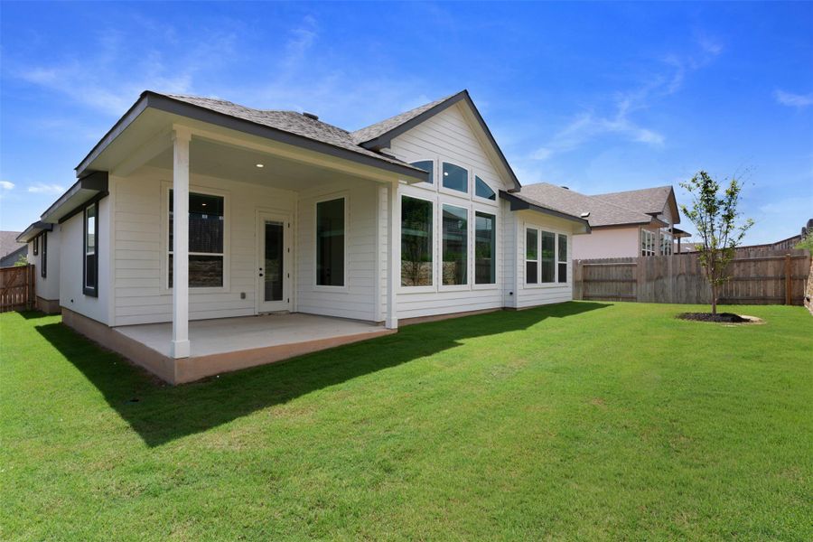 Expansive green lawn bordering a covered patio and a home with white siding Expansive green lawn bordering a covered patio and a home with white siding