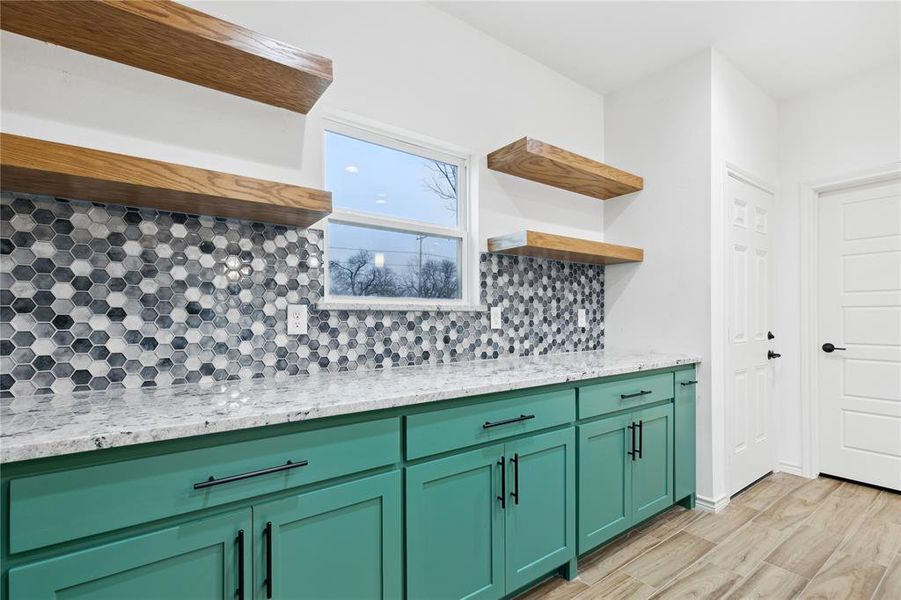 Kitchen featuring light hardwood / wood-style flooring, green cabinets, light stone countertops, and backsplash