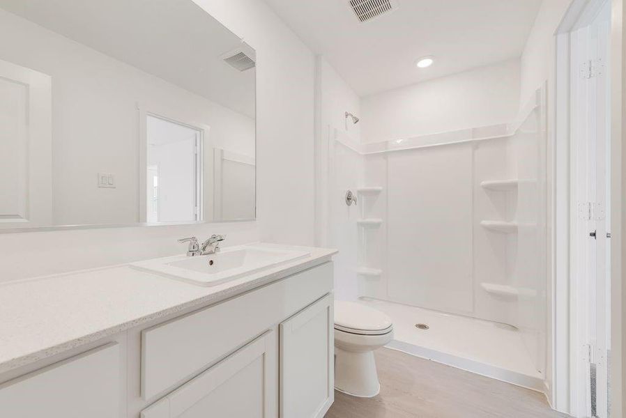 Full bath with a shower stall, vanity, and light wood-style floors