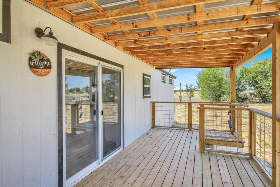 A spacious covered wooden deck looks out over the peaceful surrounding landscape.
