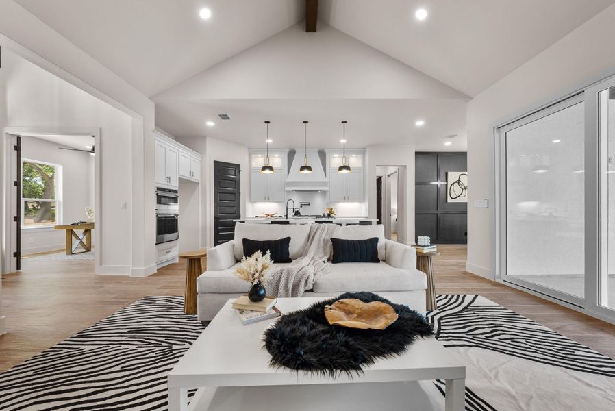 A spacious, open-concept living area with soaring vaulted ceilings flows into a sleek, modern kitchen.