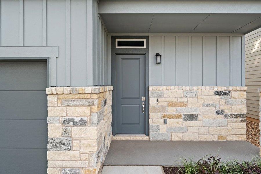 Entrance to property featuring board and batten siding, stone siding, and a porch