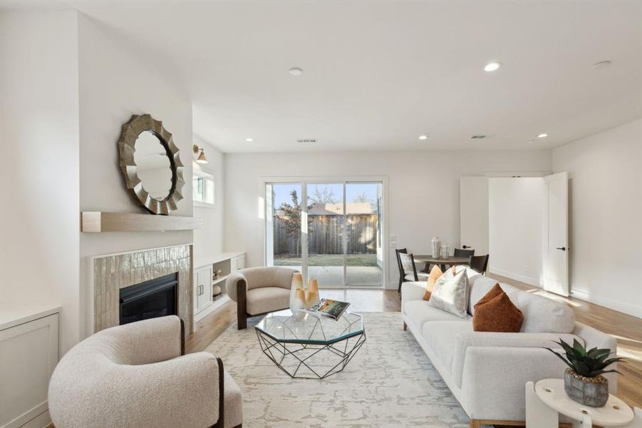 Living room with a tiled fireplace and light hardwood / wood-style flooring