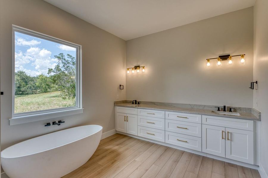 Indulge in a tranquil retreat with a freestanding tub and double vanity, overlooking serene outdoor views.