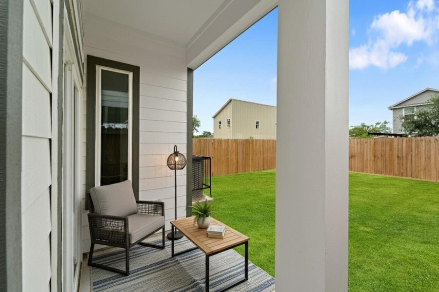 This ground-level covered patio area has a tiled floor, leading out to a grassy, fenced backyard.