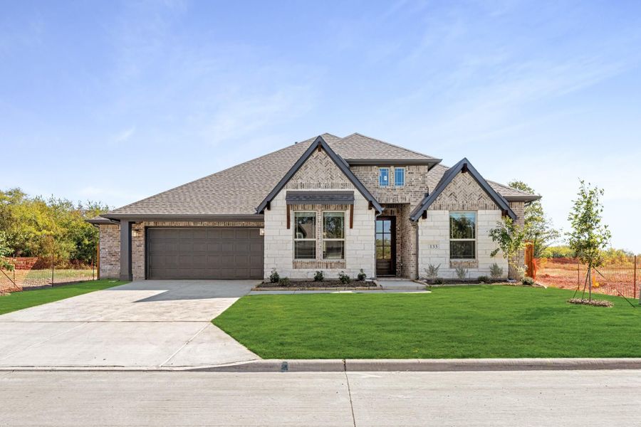 Single-story home with brick and stone exterior, two-car garage, and green front lawn Single-story home with brick and stone exterior, two-car garage, and green front lawn