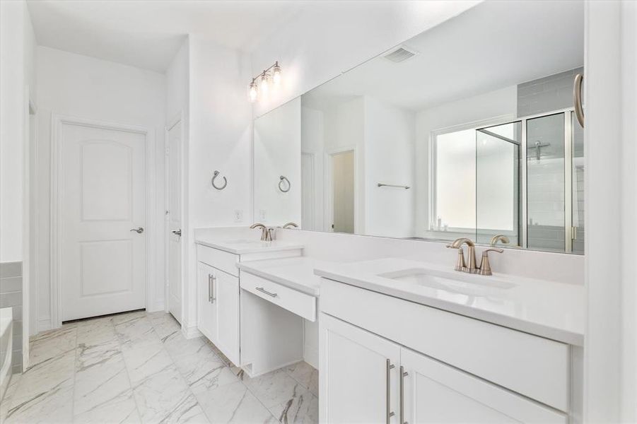 Bathroom featuring double vanity, a stall shower, light marble finish floors, and a garden tub