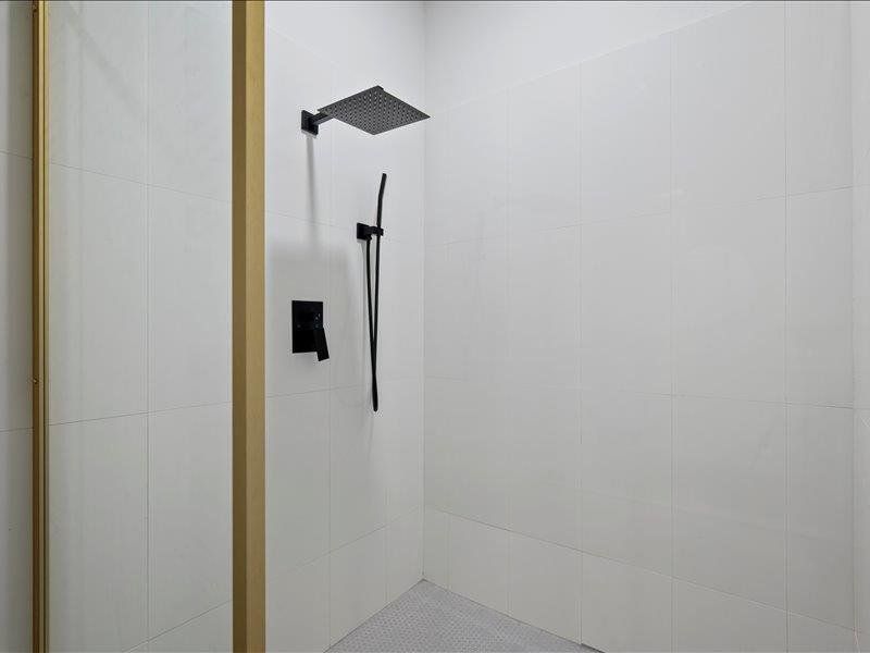 The shower features a matte black rain shower head and a handheld shower wand