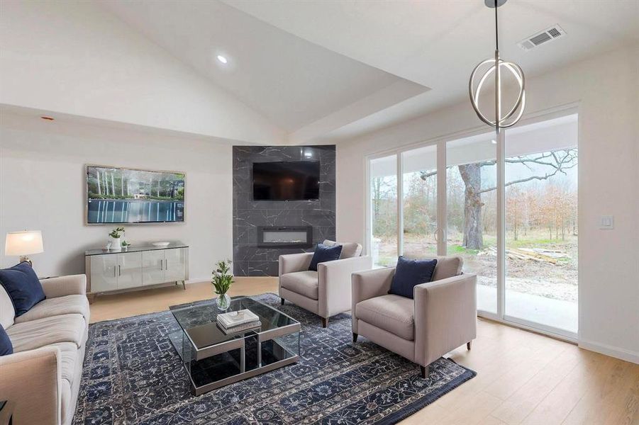 Living room featuring visible vents, high vaulted ceiling, wood finished floors, a fireplace, and baseboards