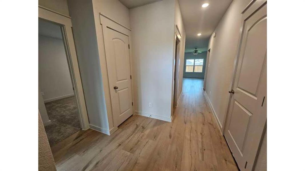 Hallway featuring wood-finish flooring, recessed lighting, and white paneled doors