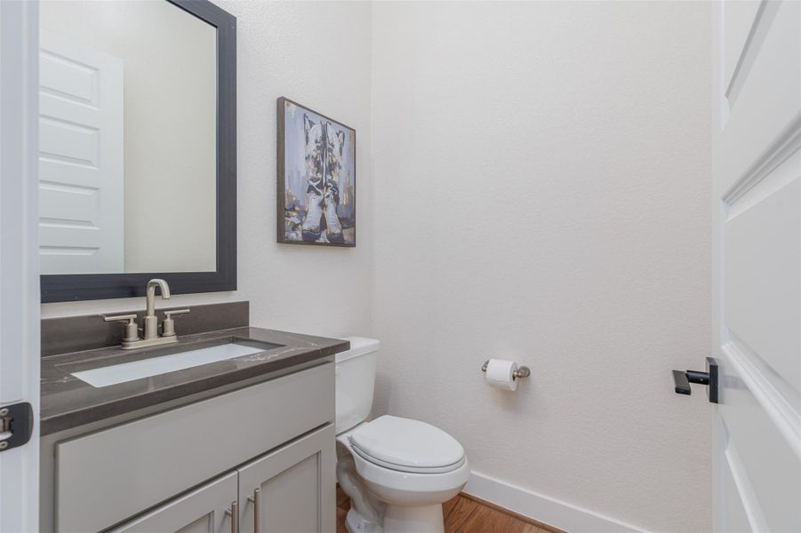 A contemporary powder bath with the continued matching cabinetry, elegant quartz surface and framed mirror.