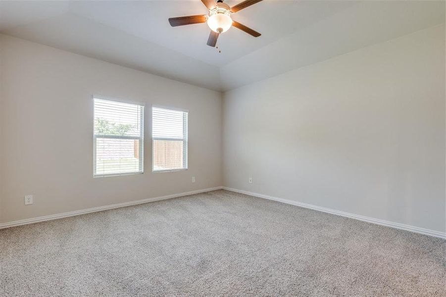 Carpeted empty room with ceiling fan and vaulted ceiling