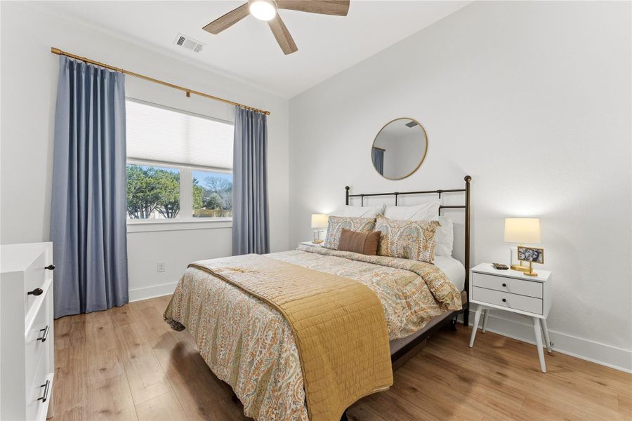 Bedroom with light wood-style floors, ceiling fan, and vaulted ceiling