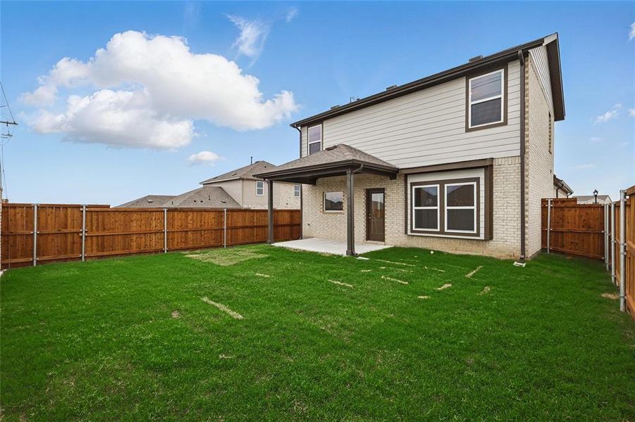 Rear view of property featuring brick siding, a patio, and a fenced backyard
