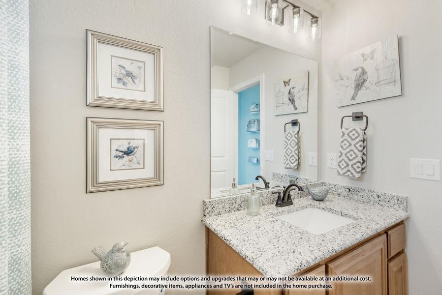 Bathroom with granite countertop vanity, large mirror, wood cabinets, and decorative wall art Bathroom with granite countertop vanity, large mirror, wood cabinets, and decorative wall art