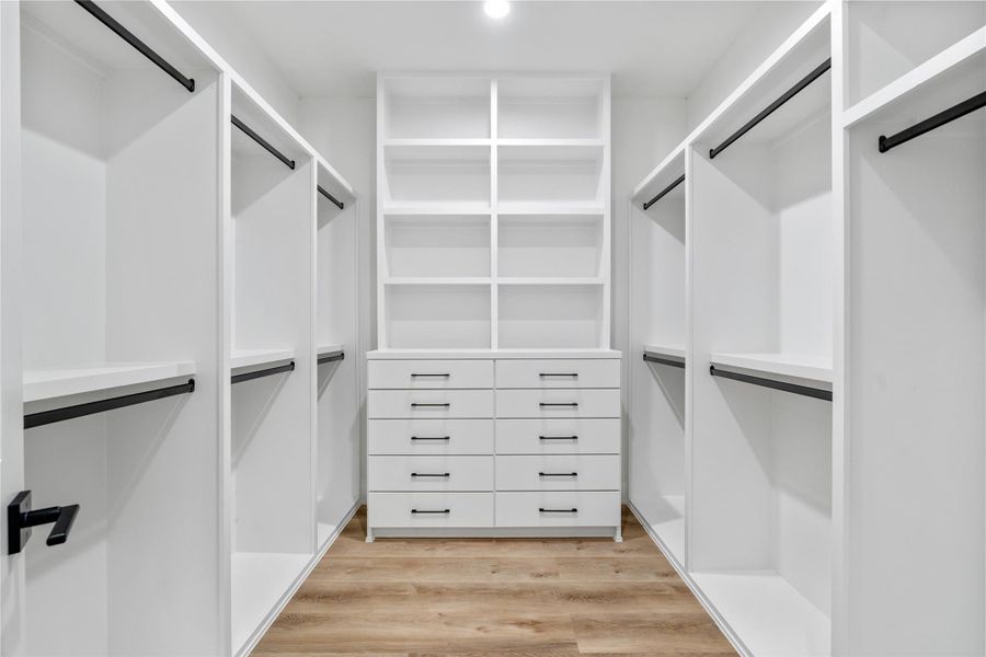 A luxurious walk-in primary closet, designed for maximum organization and style. This expansive space offers a blend of custom-built storage solutions and a sleek, modern design to keep everything effortlessly organized. A luxurious walk-in primary closet, designed for maximum organization and style. This expansive space offers a blend of custom-built storage solutions and a sleek, modern design to keep everything effortlessly organized.