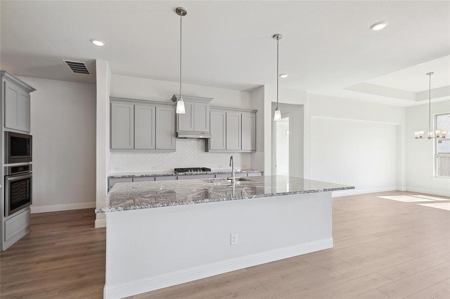 Kitchen featuring sink, light hardwood / wood-style flooring, stainless steel appliances, and stone countertops