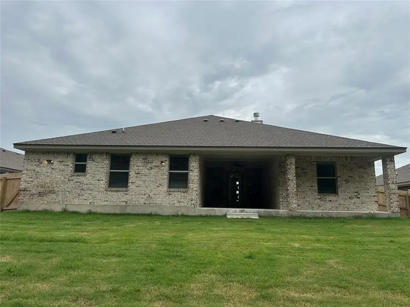 Back of property featuring brick siding and a shingled roof