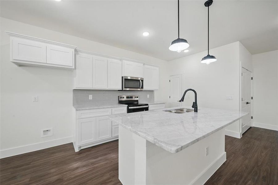 Kitchen with backsplash, a sink, dark wood-style floors, stainless steel appliances, and white cabinets Kitchen with backsplash, a sink, dark wood-style floors, stainless steel appliances, and white cabinets