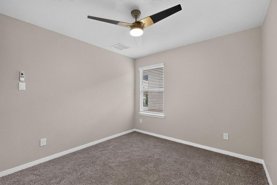 Plush carpeting and a classic single window define this versatile secondary bedroom space.