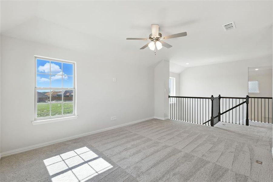 Spare room featuring light carpet, lofted ceiling, and ceiling fan Spare room featuring light carpet, lofted ceiling, and ceiling fan