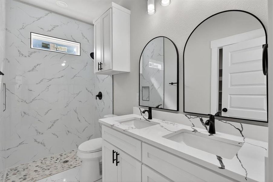 Dual vanity featuring white cabinetry, integrated sinks, and stone-finish countertops with pronounced veining