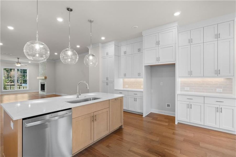 Kitchen featuring open floor plan, dishwasher, light wood-style floors, backsplash, and ceiling fan