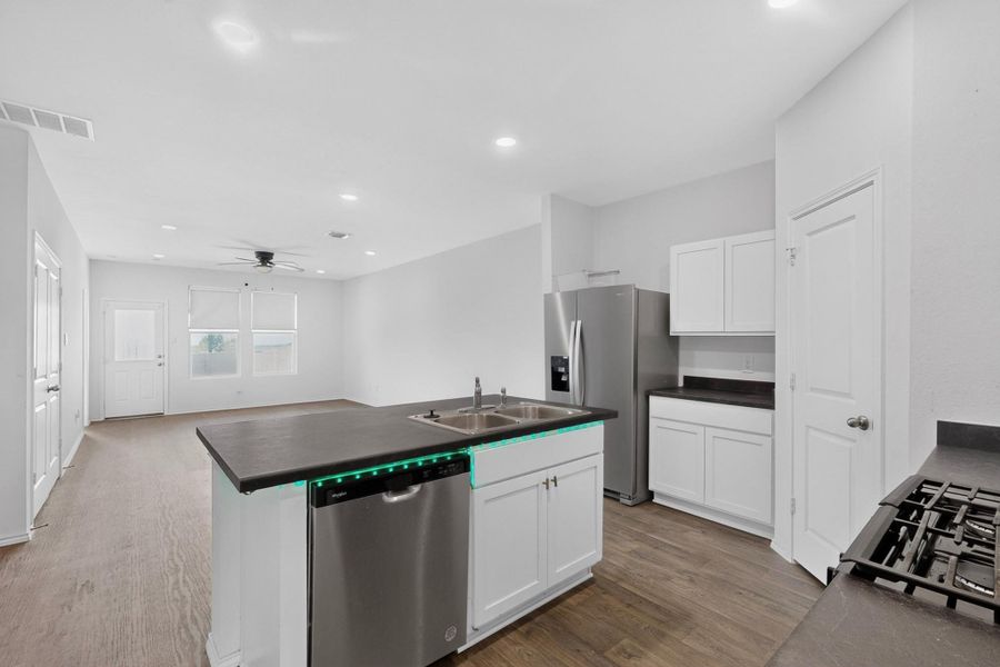 Gleaming wood-look floors anchor this airy, open-concept space seamlessly connecting kitchen and living areas. Gleaming wood-look floors anchor this airy, open-concept space seamlessly connecting kitchen and living areas.