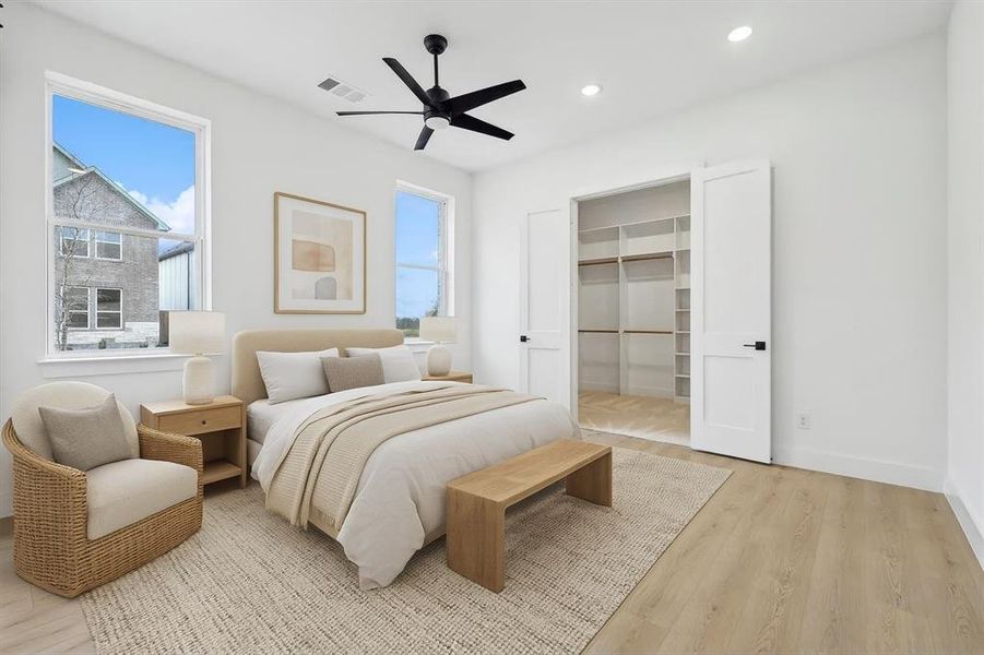 Bedroom featuring light wood-style floors, a spacious closet, recessed lighting, virtually staged