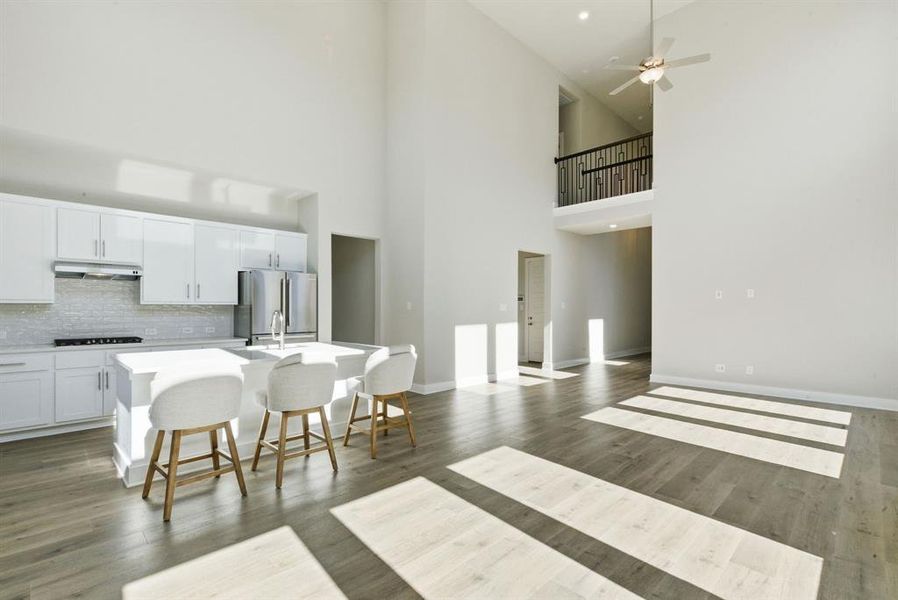 Kitchen featuring white cabinets, an island with sink, a kitchen bar, freestanding refrigerator, and decorative backsplash