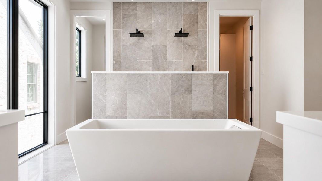 Primary bath with large tub and marble finished shower.